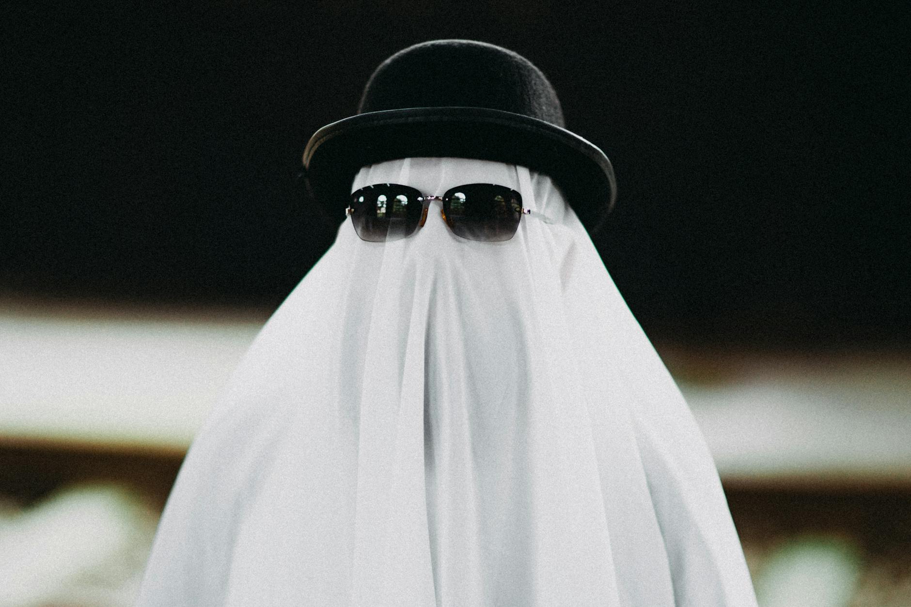person dressed as a ghost wearing a hat and sunglasses